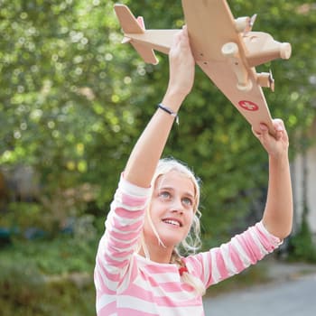 Protezione giuridica per famiglie: Bambina gioca con un aeromodello di legno