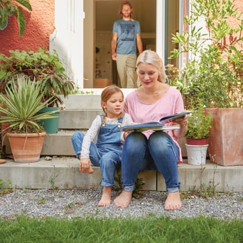 Protezione giuridica per privati: Mamma guarda con il bambino un libro illustrato in giardino