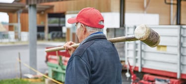 Rechtsschutz in der Landwirtschaft: Bauer trägt Holzschlegel für den Zaunbau