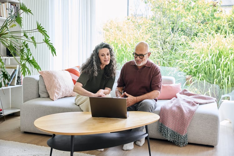 Un couple est assis sur le canapé et fait des recherches sur un ordinateur portable sur une question relative au droit du bail