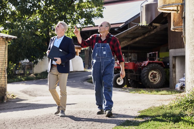 Un conseiller en assurances et un agriculteur discutent à la ferme