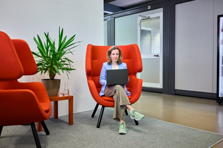 Une femme dans un fauteuil rouge effectue une recherche sur un ordinateur portable sur une question juridique