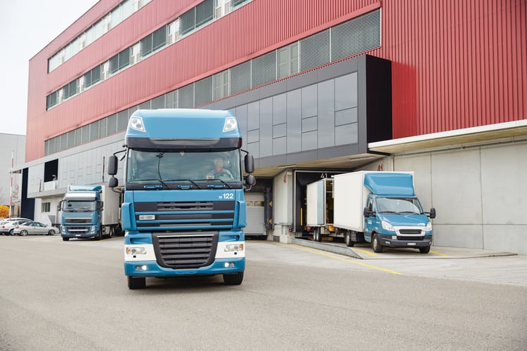 Türkisblauer Lastwagen verlässt ein Logistikzentrum 